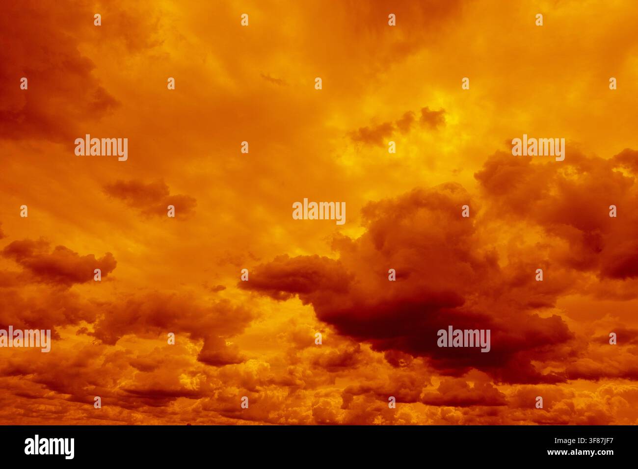 Dramatic orange and golden clouds fill the sky at sunset, creating an intense fiery atmospheric cloudscape Stock Photo