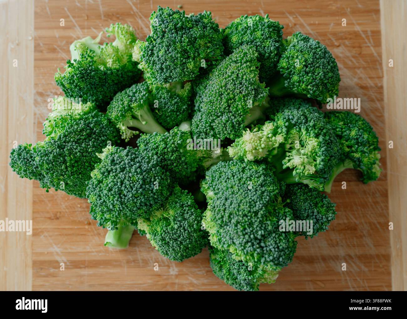 Broccoli arranged on a cutting board, in wooden surface, with broccoli, cutting board, from a top-down view perspective, with green, brown accents Stock Photo