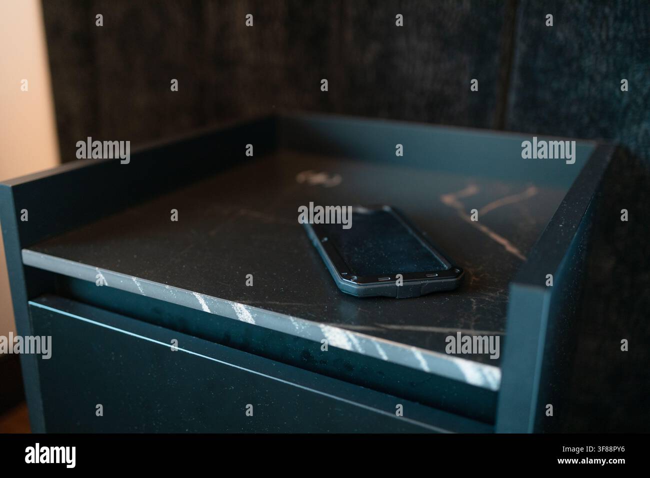 Modern smartphone lying on dark marble bedside table top Stock Photo