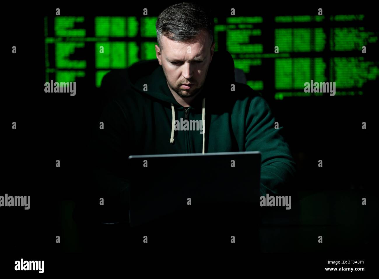 Hacker types code on laptop keyboard. Hacker analyzes system vulnerability at night. Hacker monitors server and database access. Hacker launches cyber Stock Photo