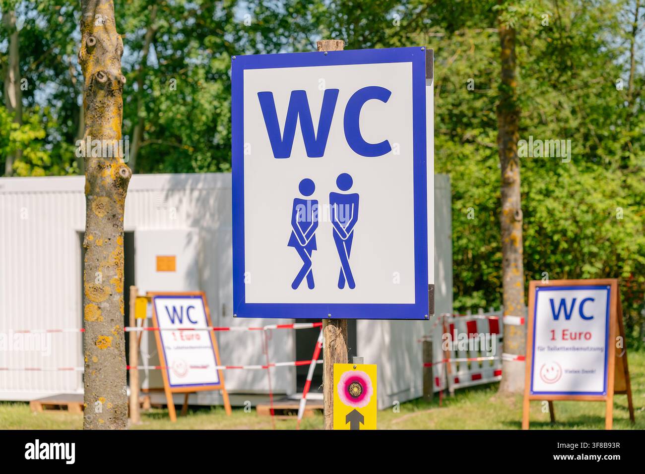 Public toilet zone in a park with portable WC cabins and directional signboards. Perfect stock image for public infrastructure, temporary event Stock Photo