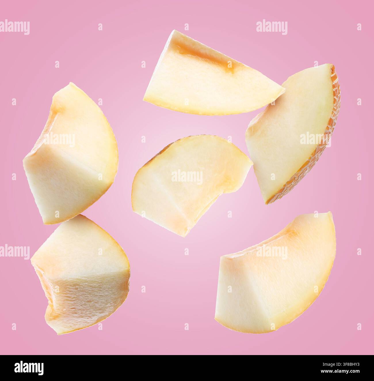 Pieces of melon flying in air on pink background Stock Photo