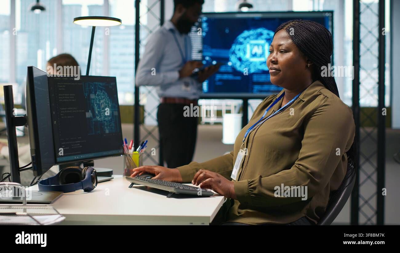 Female admin using AI neural networks tech on computer to optimize performance and forecast issues. Woman in office training artificial intelligence deep learning models using PC, camera A Stock Photo