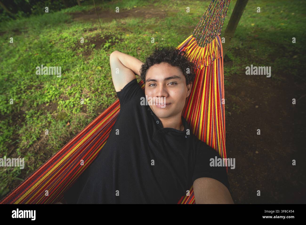 Smiling man taking a selfie while lying in a hammock. Attractive man smile resting in a hammock in nature Stock Photo