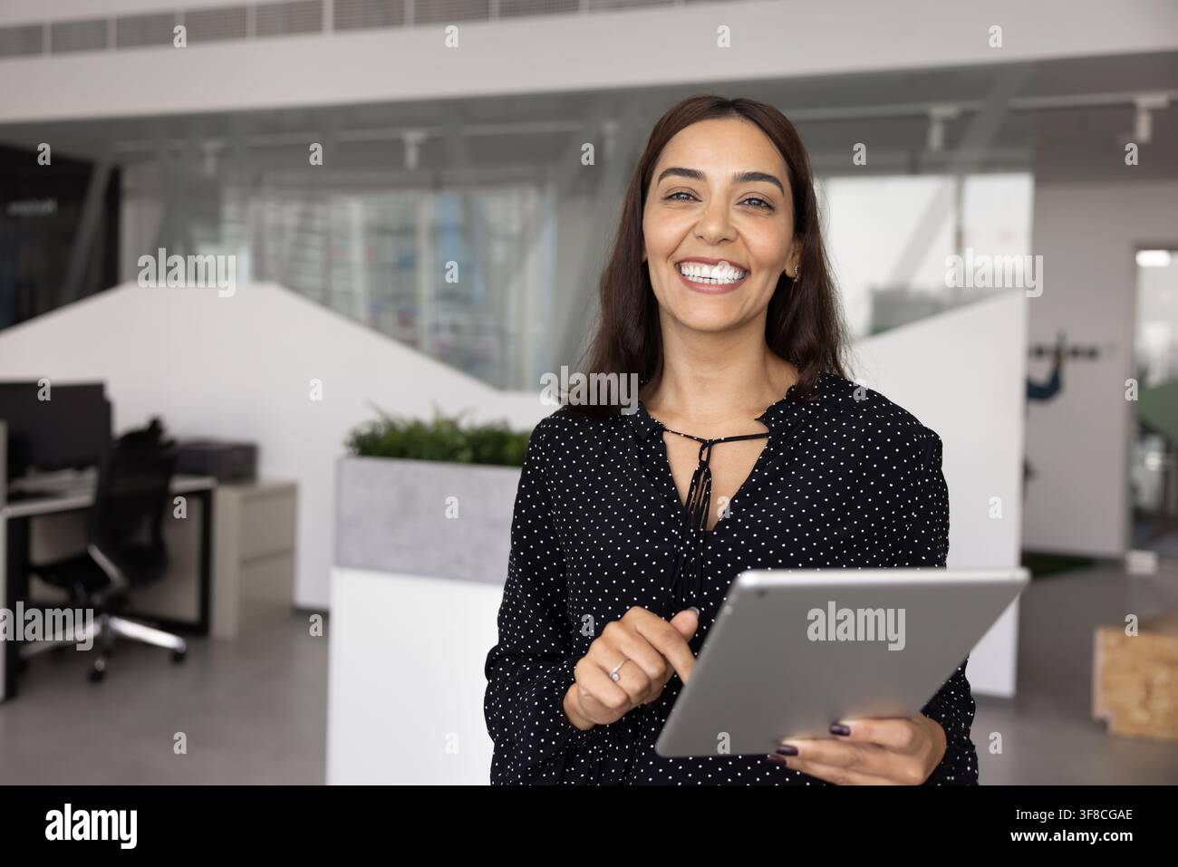 Portrait of Arabian businesslady, marketing specialist or project manager posing in office with tablet, looking at camera, exuding professionalism and Stock Photo