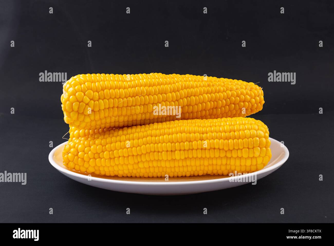 Boiled yellow waxy sweet corn cobs stack isolated on white background Stock Photo