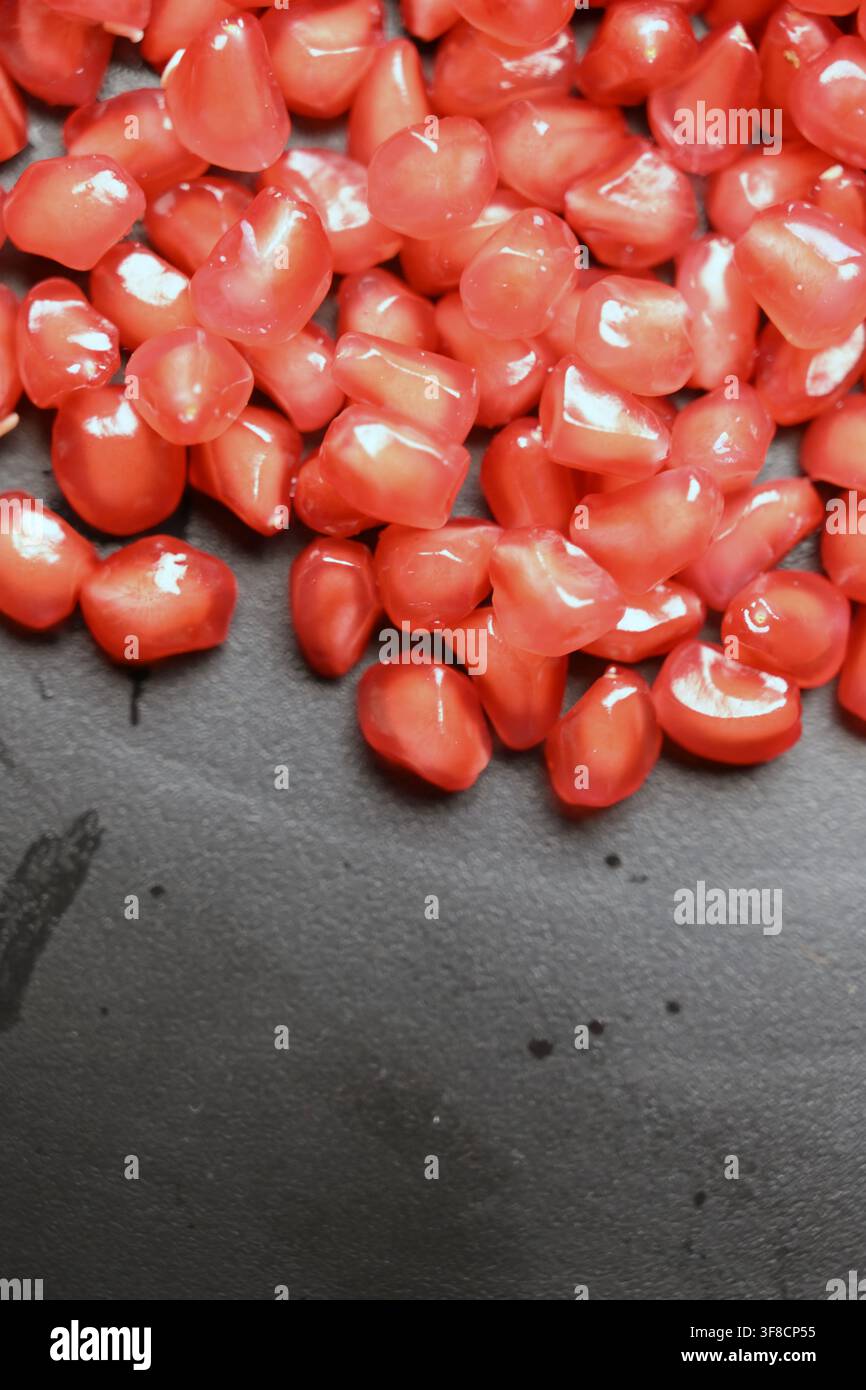 Glossy Ruby Pomegranate Seeds on Black Stone Backgrounds Stock Photo