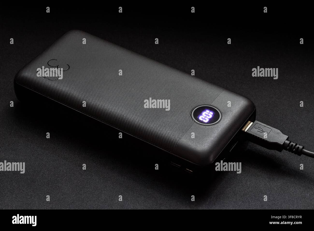 A modern power bank on a dark background. Battery for charging devices. Stock Photo