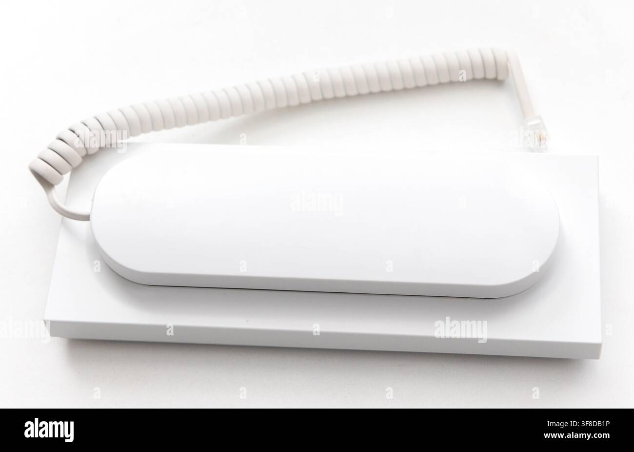 A modern white intercom handset lies on a flat surface Stock Photo