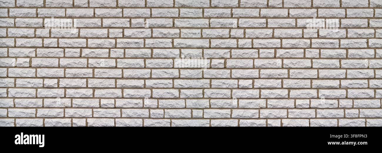 Wall made of light-colored, rectangular stones and brown gaps Stock Photo
