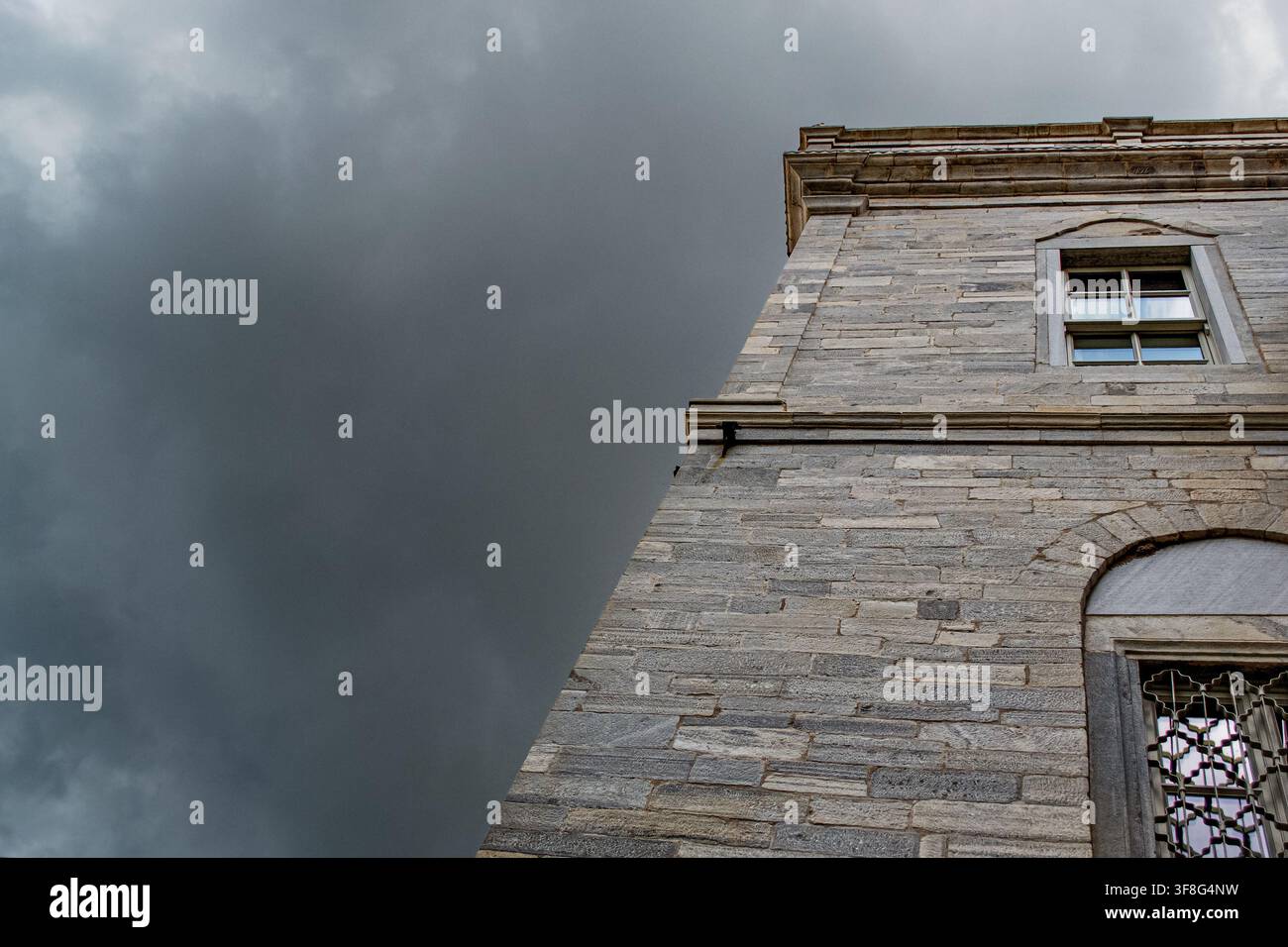 Historic Stone Building Under Dark Storm Clouds Stock Photo