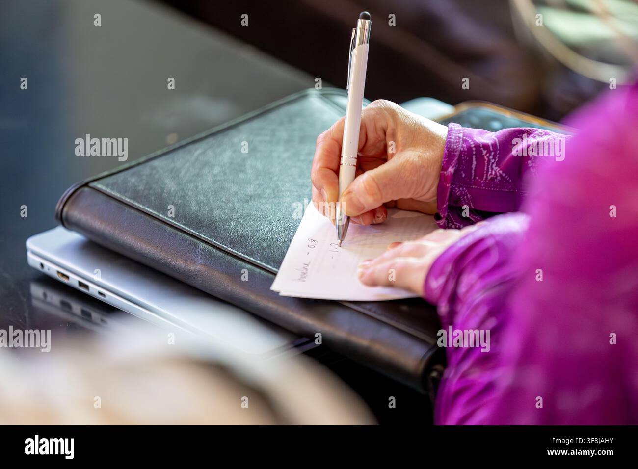 A woman's hand jots down written notes with a pen onto a notepad Stock Photo