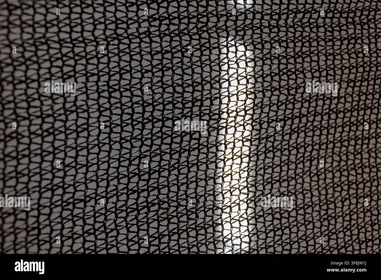 A close-up view shows a black mesh pattern with soft blurred light behind it. Stock Photo