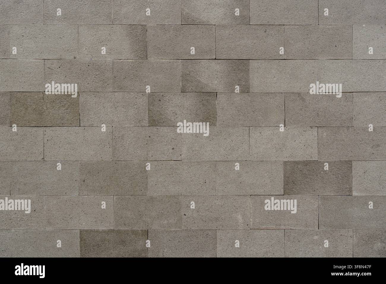 Grey rectangular stone tile wall texture in a running bond pattern background. Stock Photo