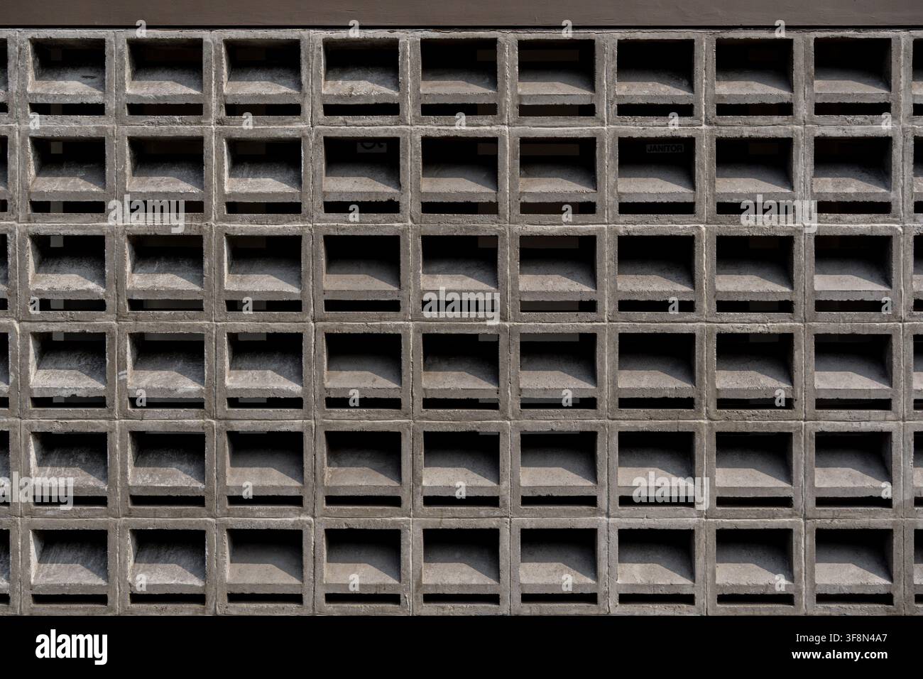 Concrete breeze block wall texture showing a repeating square grid pattern for architectural ventilation. Stock Photo