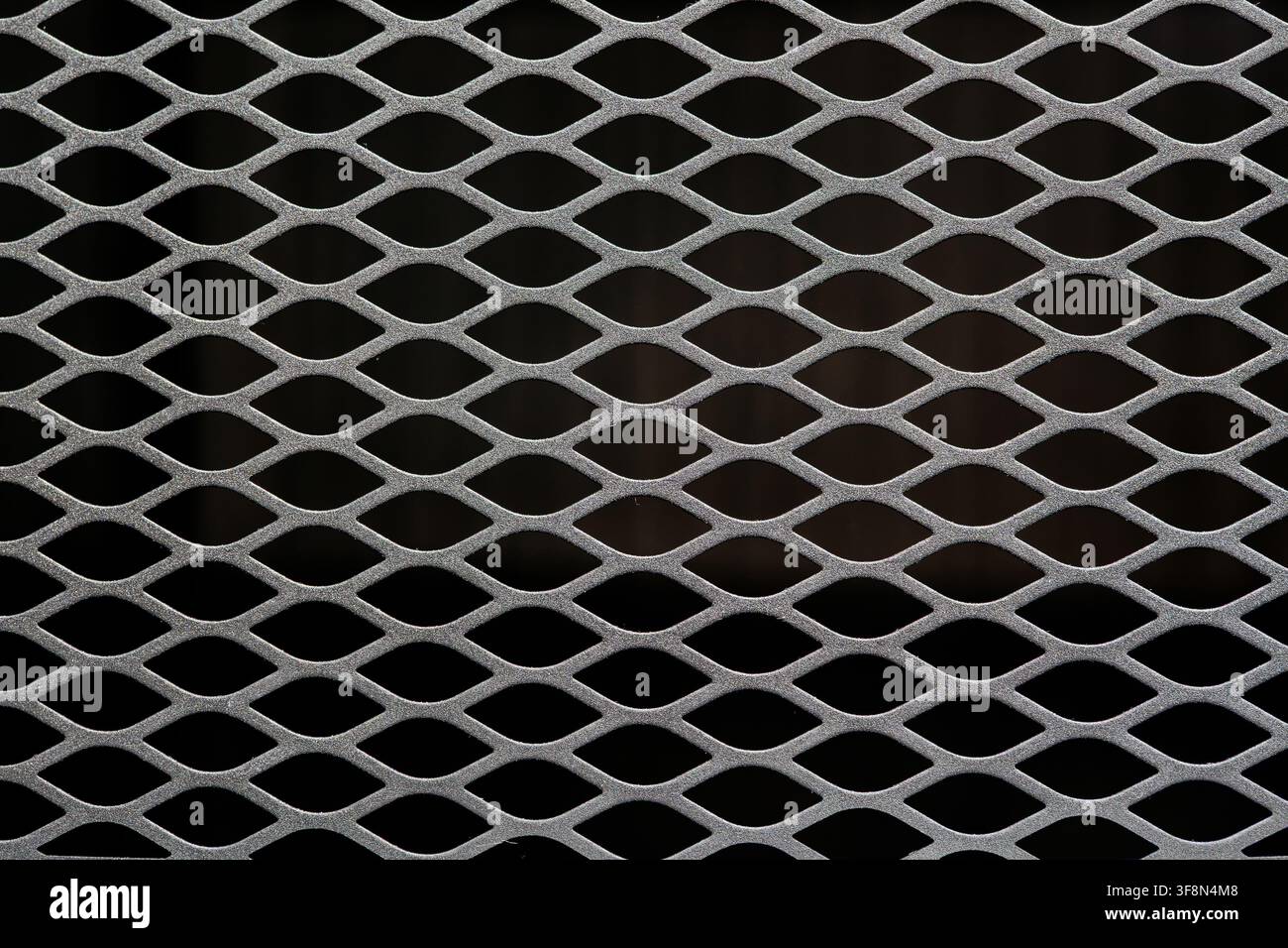 Expanded metal mesh grating with diamond pattern over dark background. Stock Photo