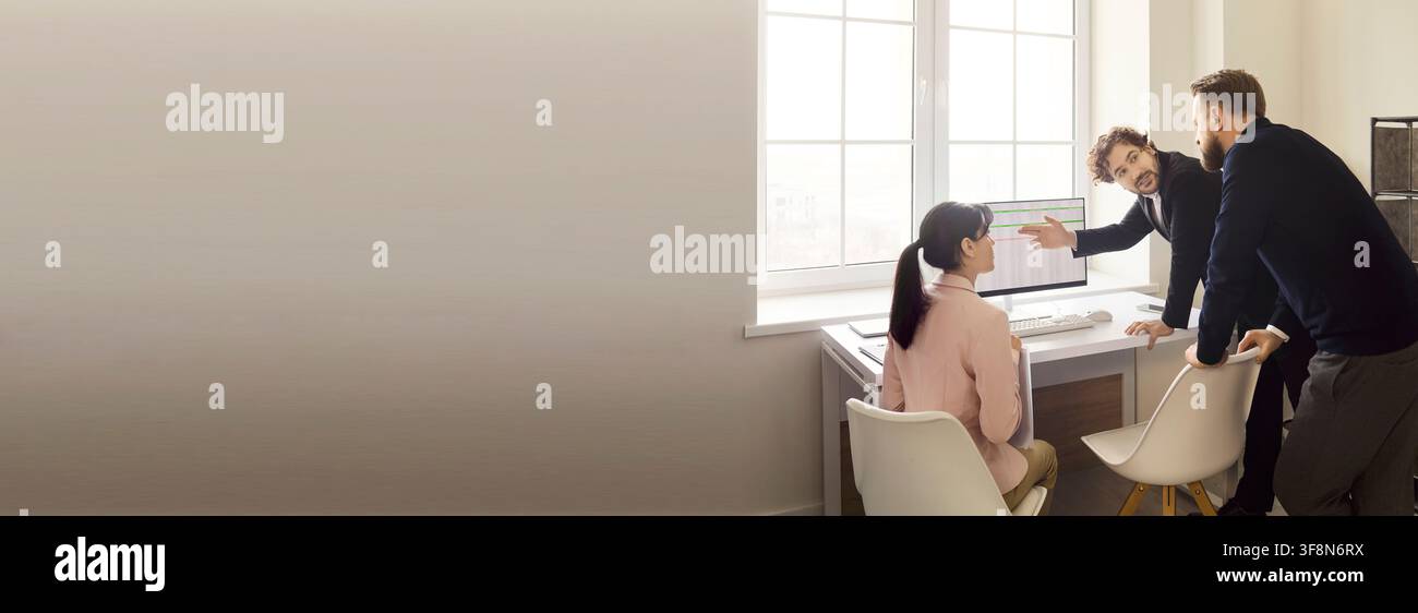 Business team analyzing dashboard data on computer in modern office, wide frame Stock Photo
