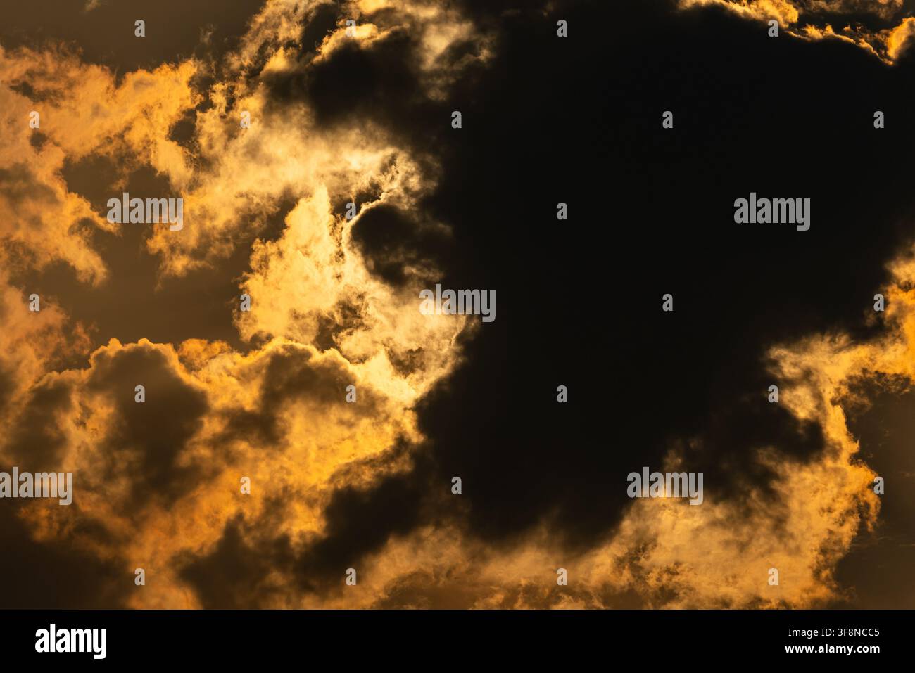 Golden sunlight breaking through dramatic dark clouds in the sky Stock Photo