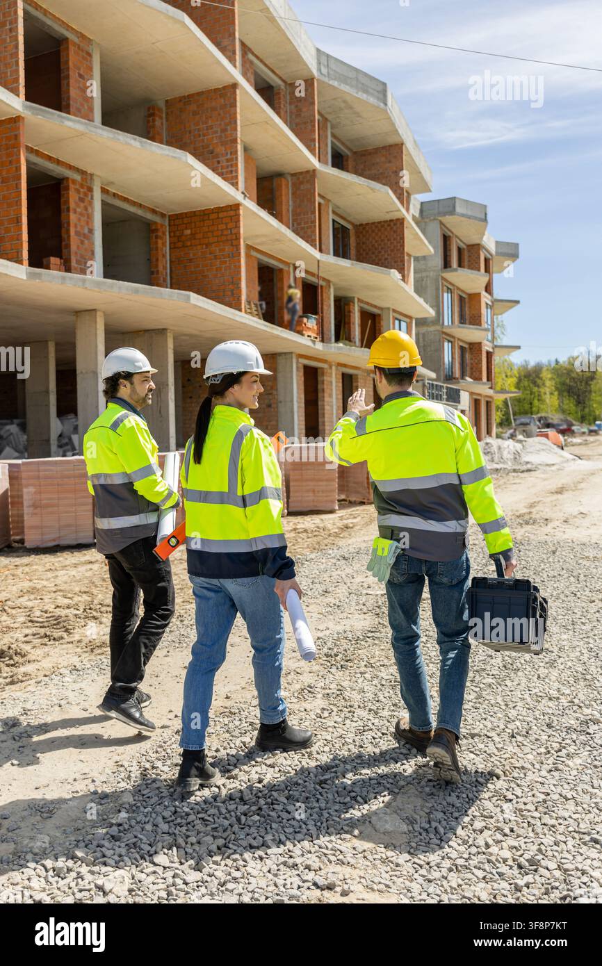Group of engineers walking on gravel path gesturing and discussing Stock Photo