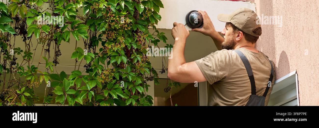 Technician Installing Security Camera on Building Wall Stock Photo