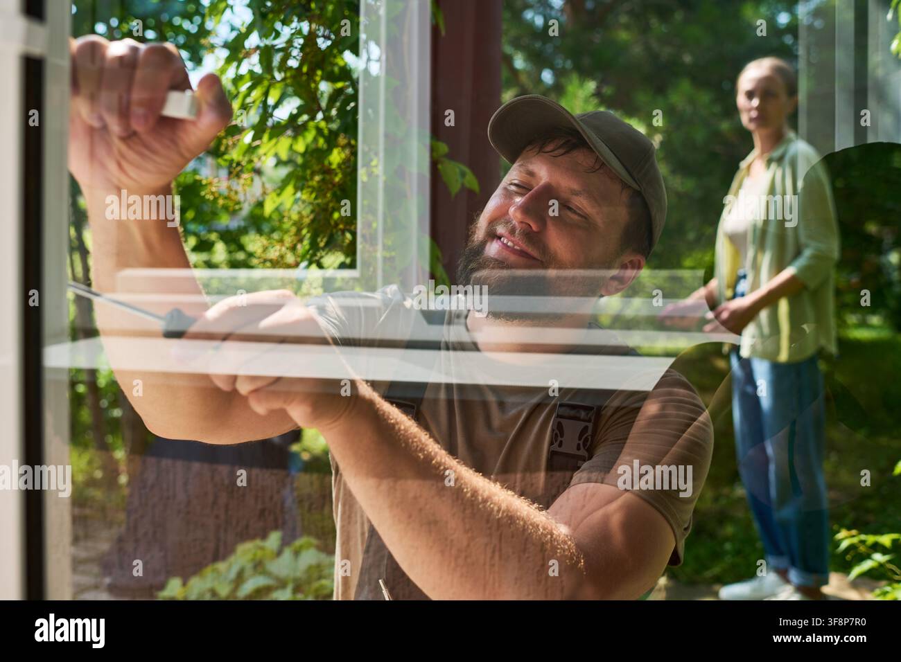 Handyman Installing Window Screen with Female Customer Watching Stock Photo