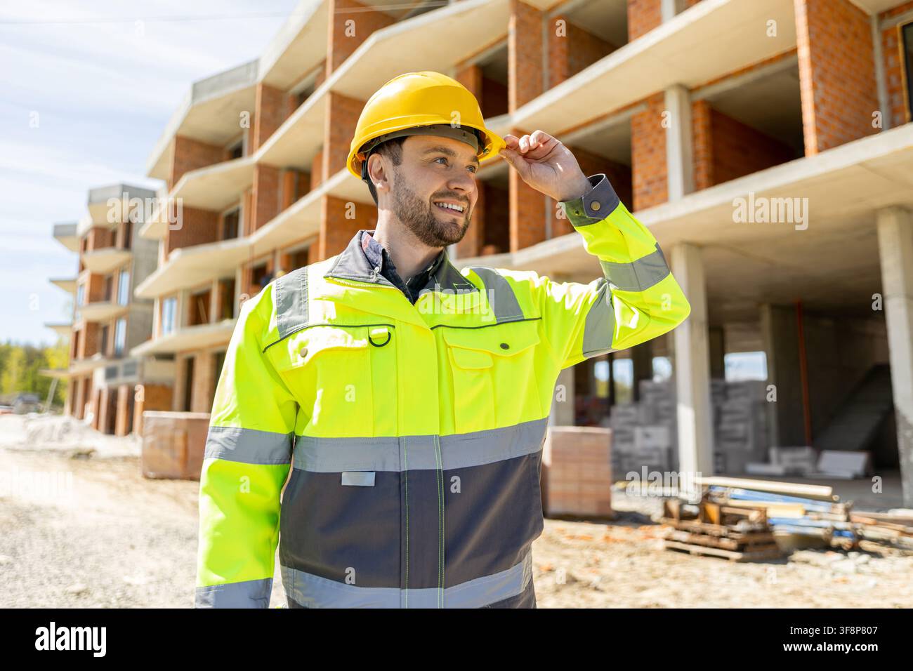 Confident construction supervisor adjusting yellow helmet Stock Photo