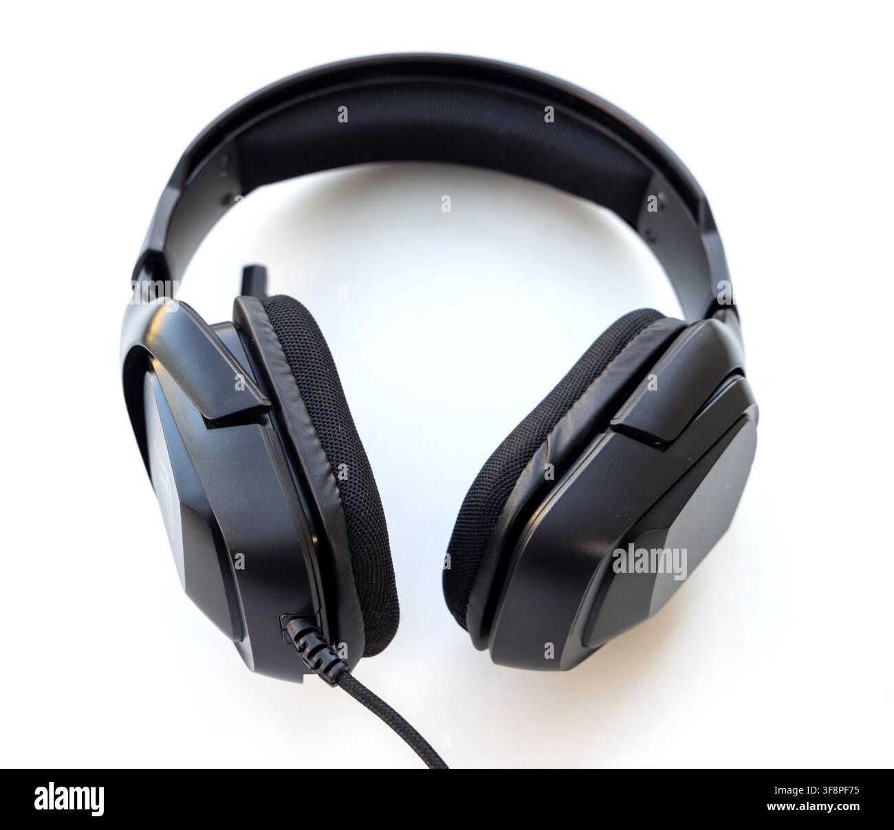 A black overear headset with a braided cable rests on white Stock Photo