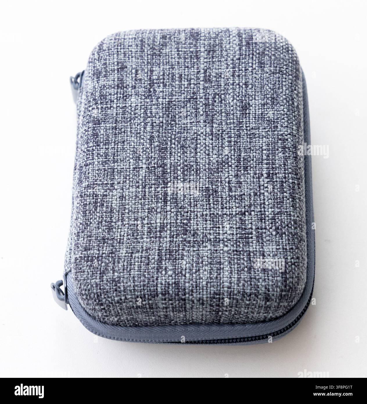 A gray fabric zippered hard case rests on a white surface Stock Photo