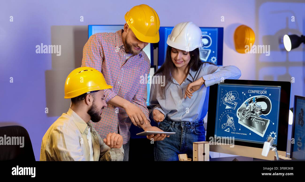 Engineering team collaborating on a digital tablet and computer screen with compressor blueprint design, the professionals wear hard hats Stock Photo