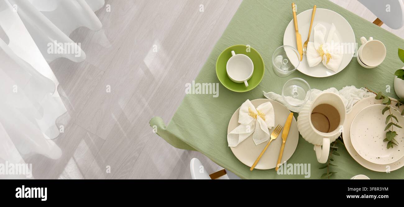 Elegant table setting with green tablecloth and gold cutlery, ready for a festive meal or special occasion Stock Photo