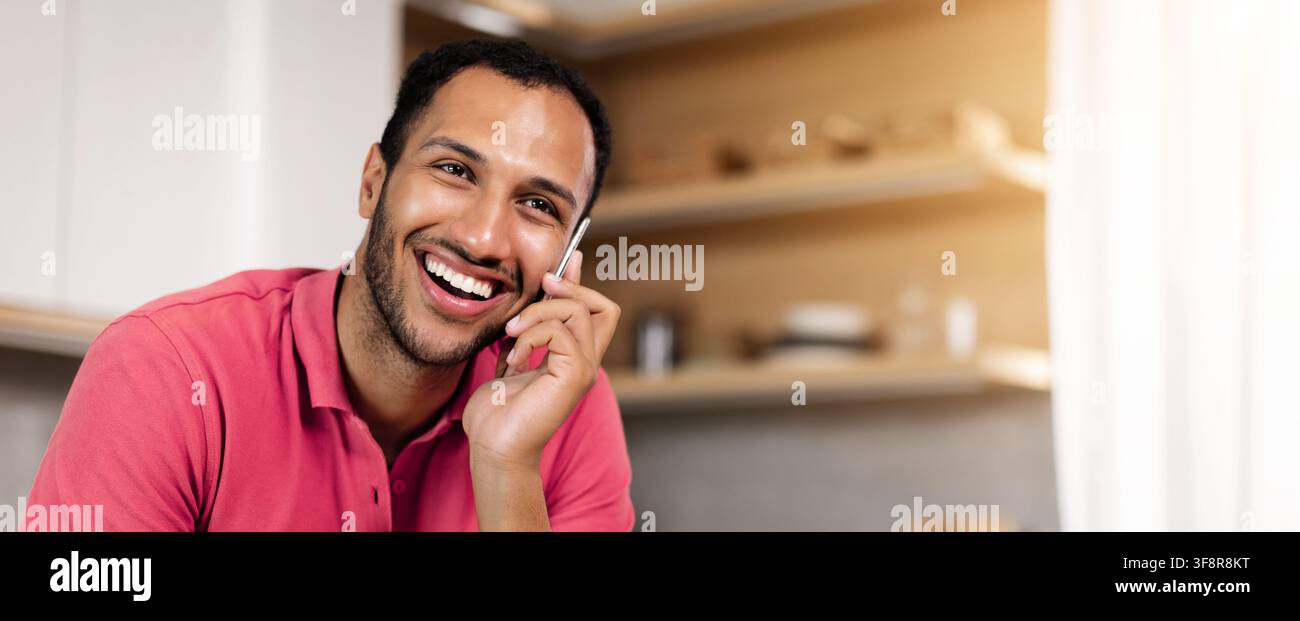 Happy Young Man Smiling While Talking On Phone At Home, Business Concept Stock Photo