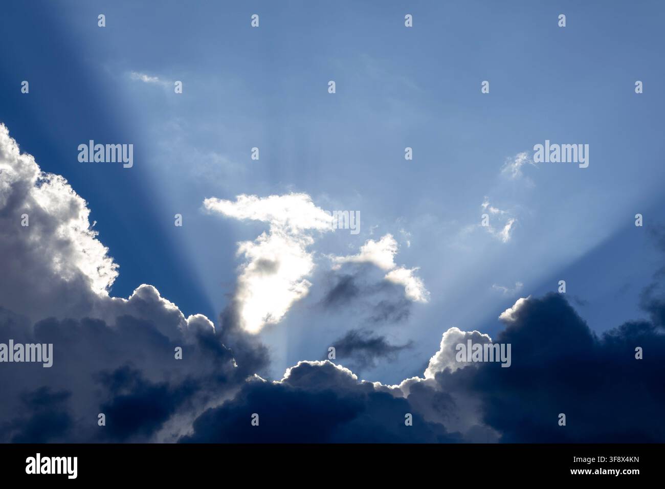 Dramatic God crepuscular rays streaming through dense dark storm clouds Stock Photo