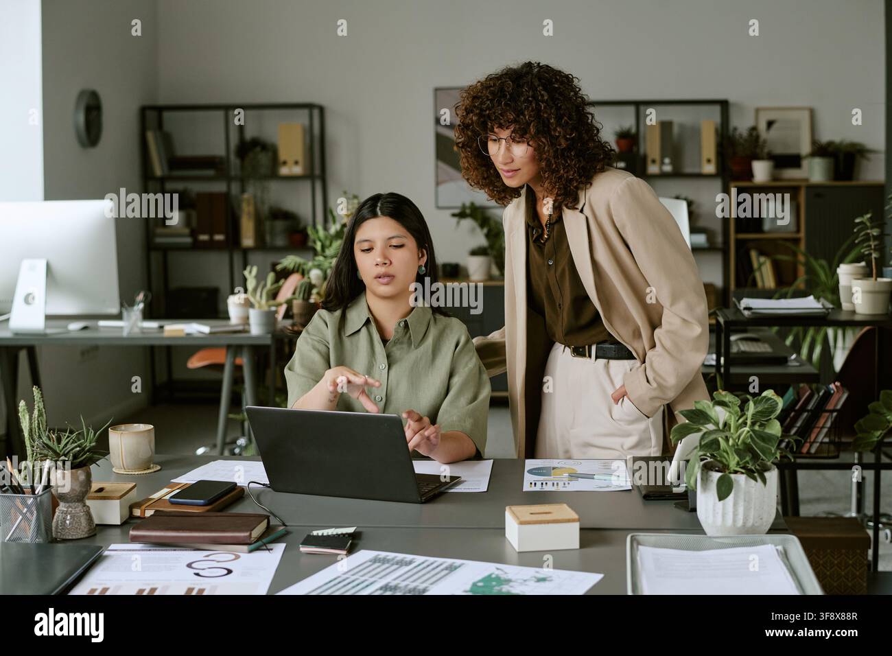 Diverse Women Collaborating on Laptop in Modern Office Stock Photo