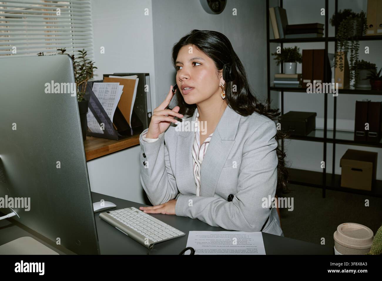 Hispanic Woman Wearing Headset Talking to Client on Computer Stock Photo