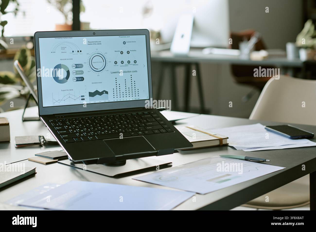 Laptop Displaying Financial Analytics on Desk in Modern Office Stock Photo