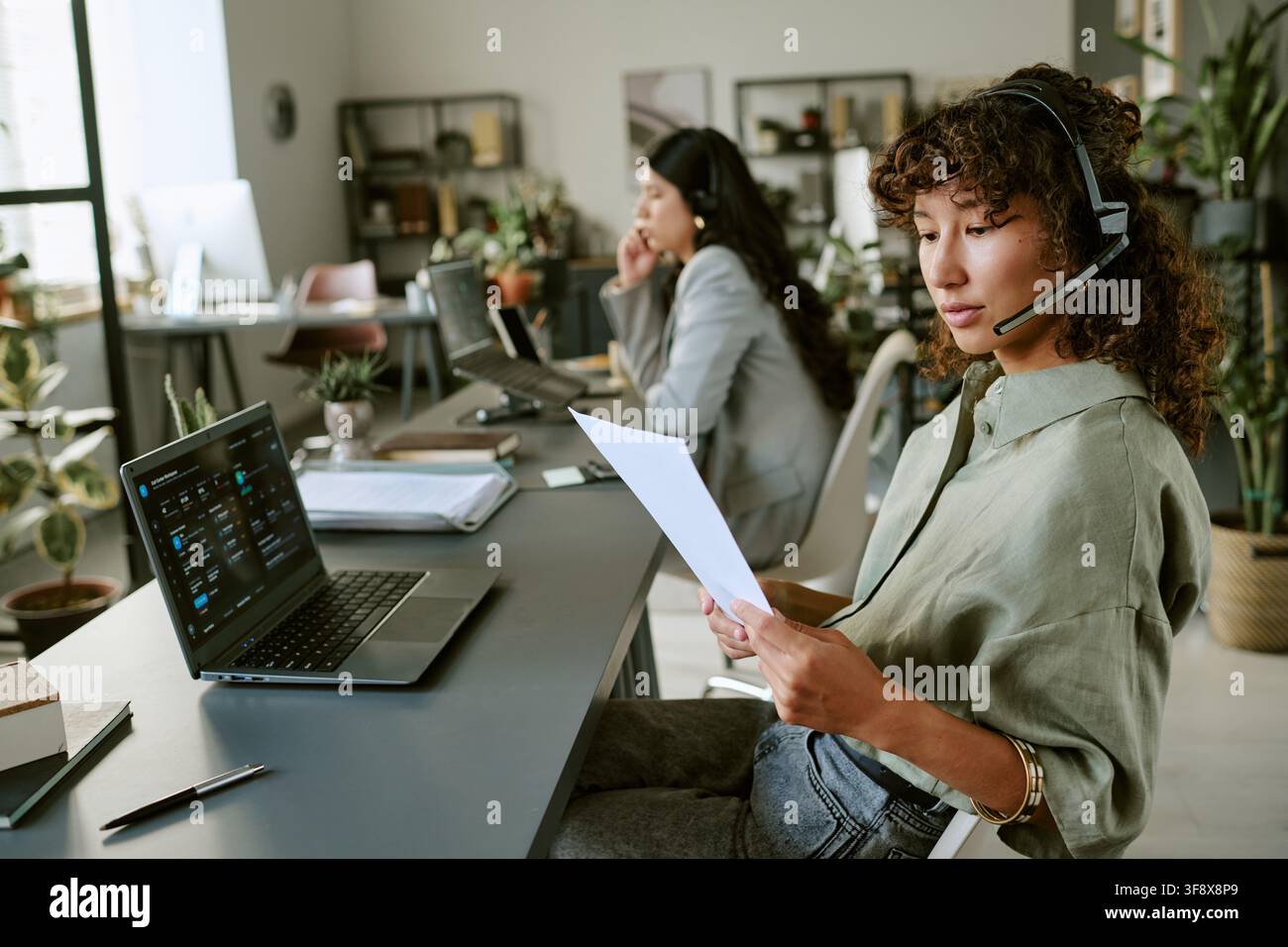 Diverse Female Agents Analyzing Data Sheets in Call Center Stock Photo