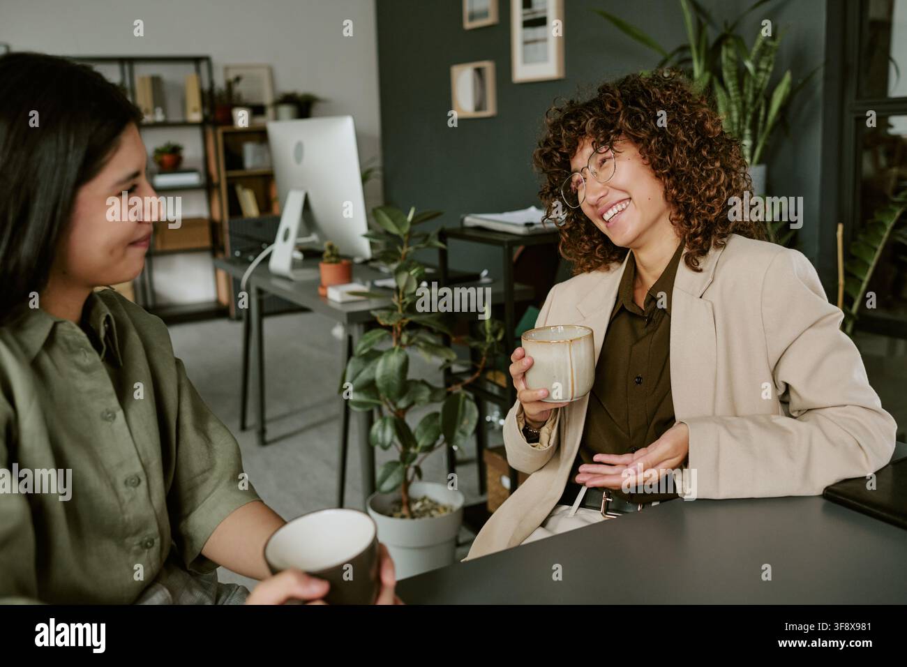 Diverse Women Talking and Drinking Coffee in Modern Office Stock Photo
