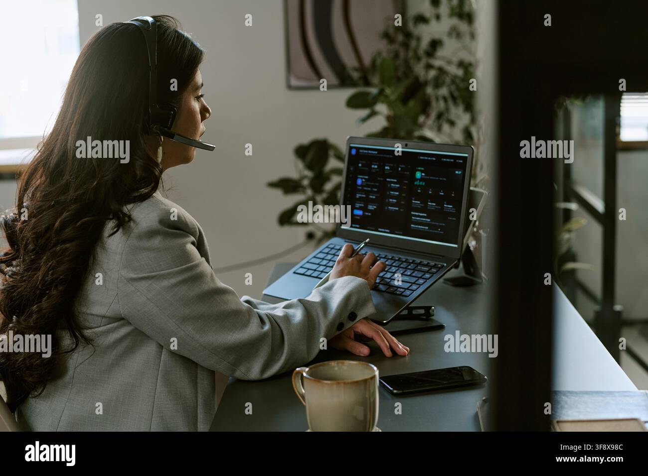 Hispanic Woman Working in Call Center Using Laptop and Headset Stock Photo