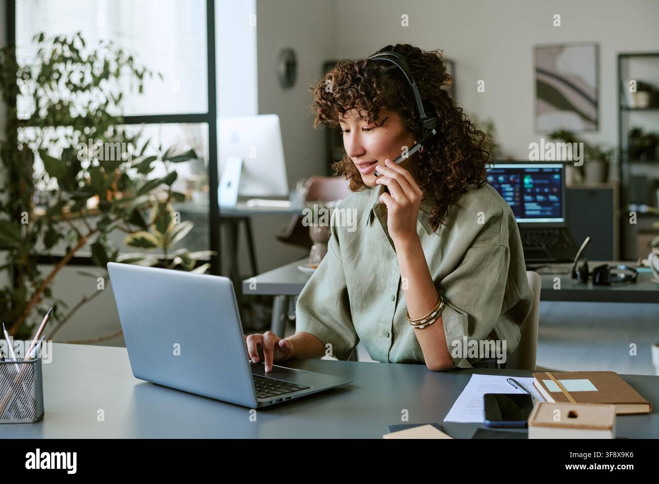 Biracial Woman Working in Call Center Using Laptop and Headset Stock Photo