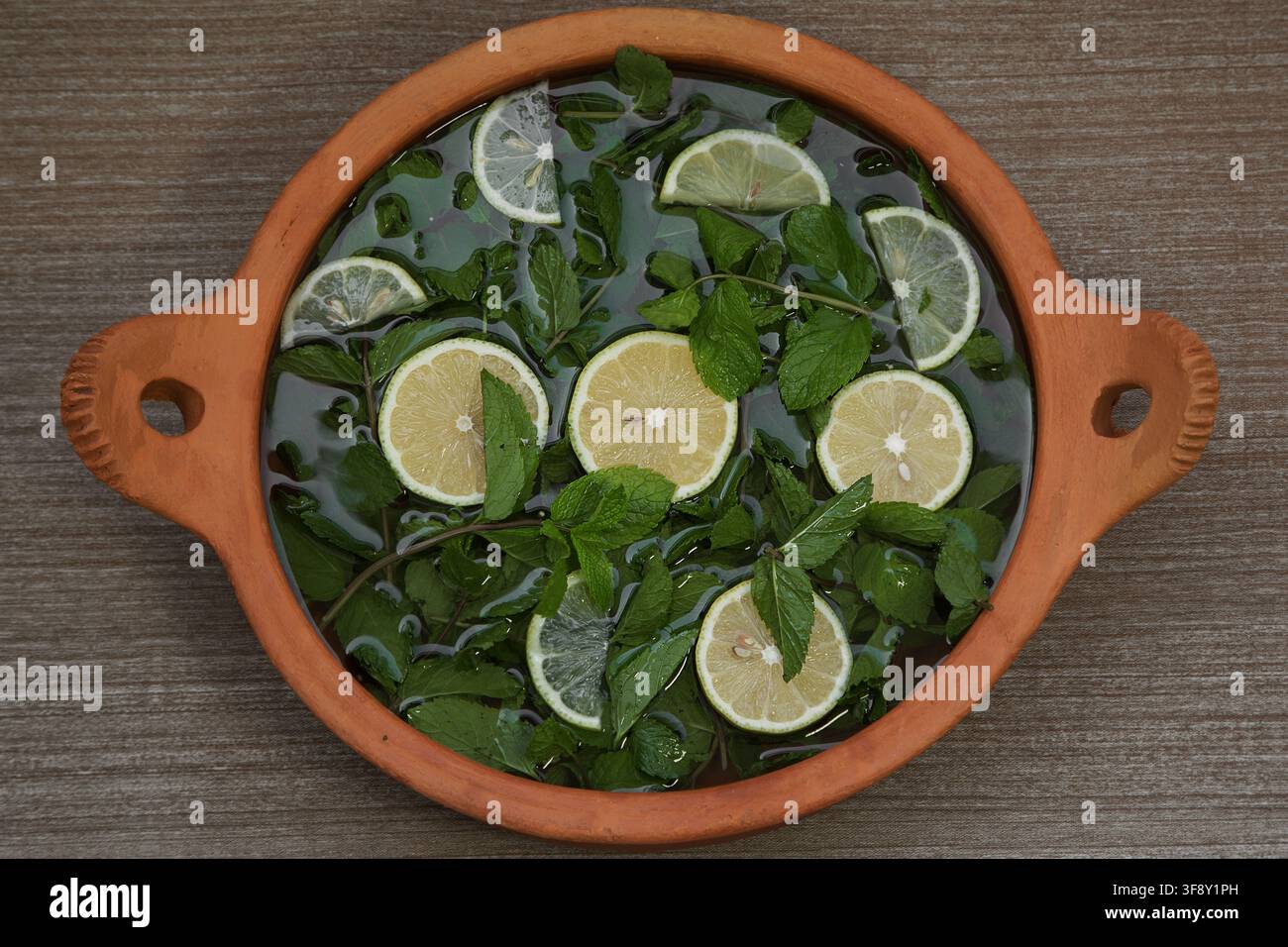 sliced lemon and ginger root with mint sprigs on a dark background Stock Photo