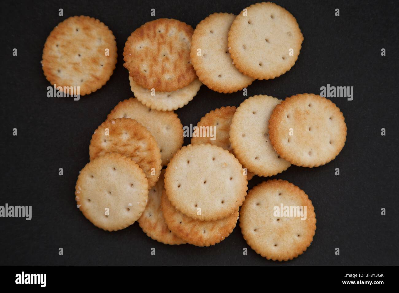 Round salted crackers on a black background. Stock Photo