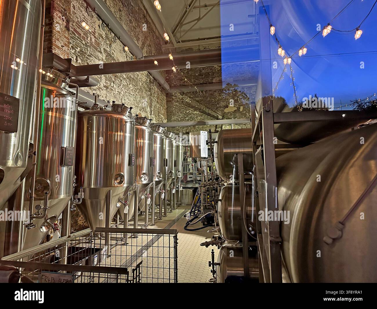 Left Handed Giant Brewpub Stainless steel brewing tanks and fermentation vessels inside a modern craft brewery in Bristol, England at dusk Stock Photo