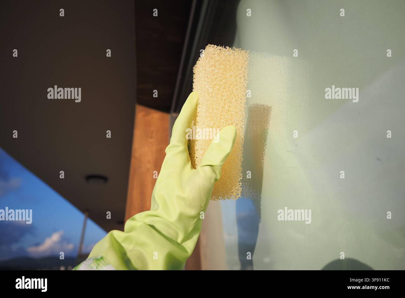 Cleaning a window with a sponge in bright daylight Stock Photo