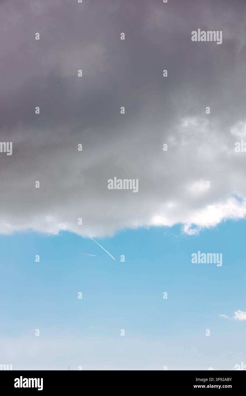 Airplane flying below ominous grey storm clouds Stock Photo