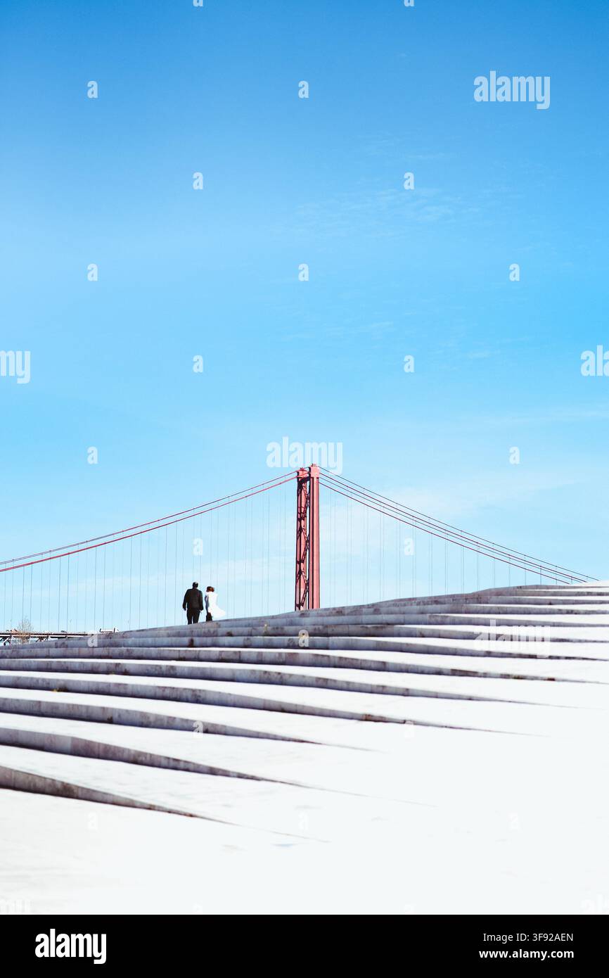 Couple walking together up steps under blue sky Stock Photo