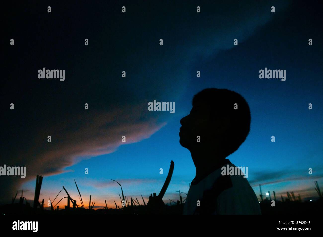 Silhouette of a boy watching a dramatic stormy sunset sky Stock Photo