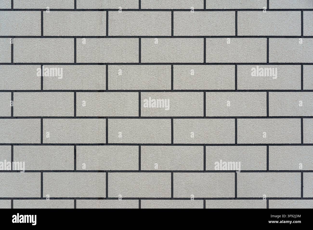 Full frame texture background featuring a clean, seamless running bond pattern of rectangular off-white or beige textured stone blocks. Stock Photo