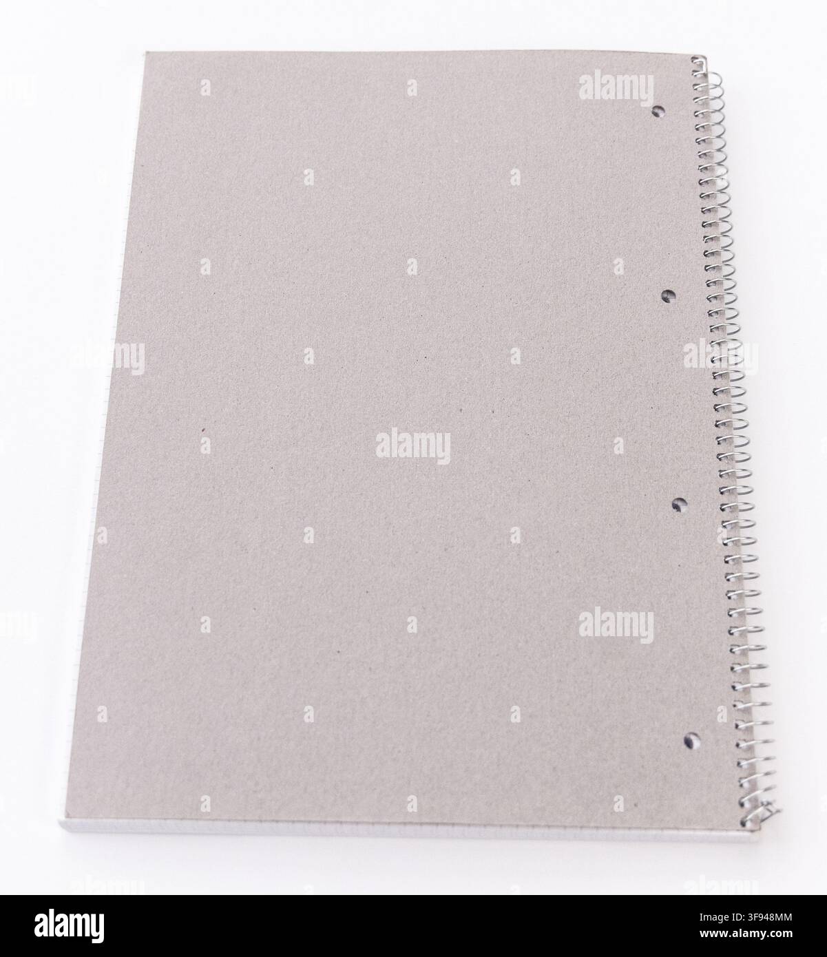 A plain grey spiral notebook rests on a clean white background Stock Photo