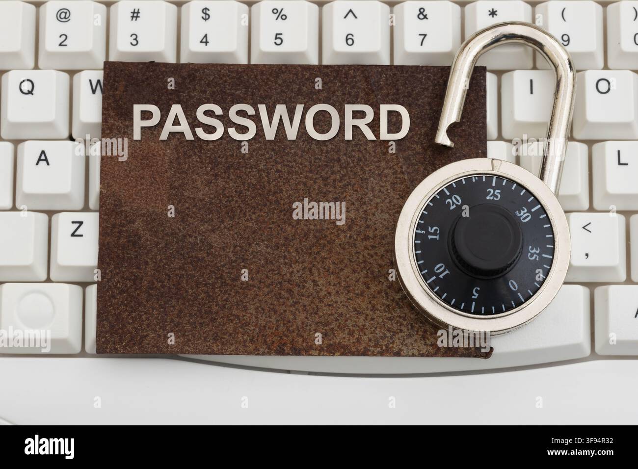 Password text on a rusty sign with combination lock on a white computer keyboard for old and weak authentication Stock Photo