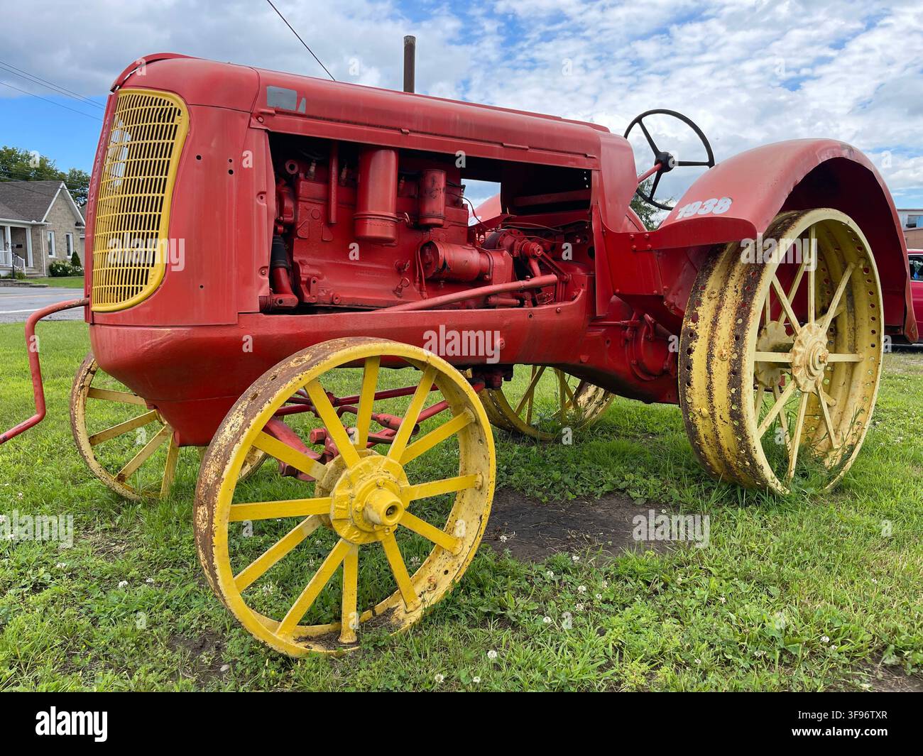 Restored 1938 vintage Massey-Harris farm tractor with red body, yellow steel wheels and exposed engine on display in Plaisance, Quebec, Canada. - Smartphone Captured Stock Image